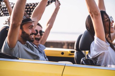 Arkadaşlar üstü açık arabada eğleniyor.