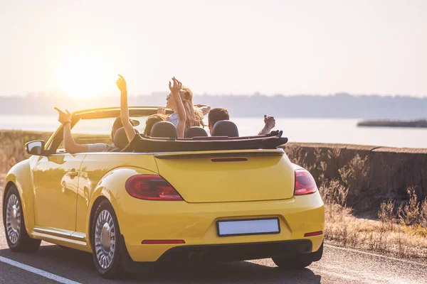 Czterech Przyjaciół Podróżuje Żółtym Kabrioletem — Zdjęcie stockowe