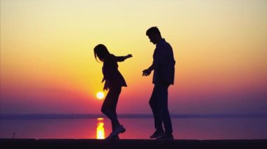 Erkek ve kadın yürür ve sarılır güzel günbatımına karşı