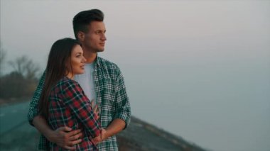 Genç adam ve kadın dışarıda birbirlerine sarılıyorlar.