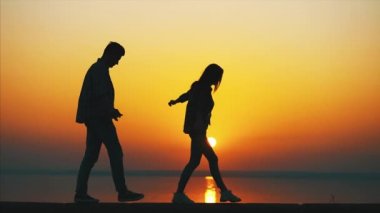 Çift güzel gün batımına karşı yürür ve sarılır.