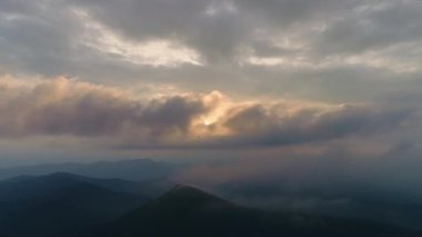 Günbatımı arka planında bir dağın üstünde bulutlar içinde uçmak. Hiperlapse