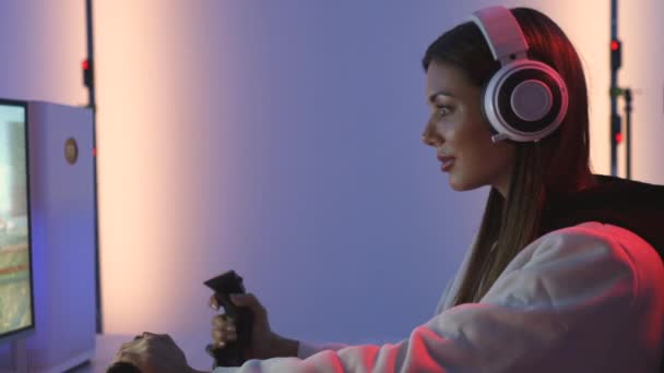 ヘッドフォンを持つ笑顔のゲーマーの女の子は青い光スタジオでビデオゲームをプレイ — ストック動画