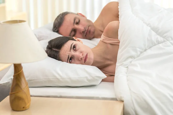 落ち込んでいる女性はベッドの上で男の近くに横たわっていた — ストック写真