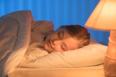 Yatakta uyuyan tatlı kız. Akşam vakti.