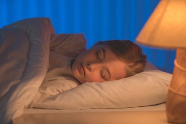 Yatakta uyuyan tatlı kız. Akşam vakti.