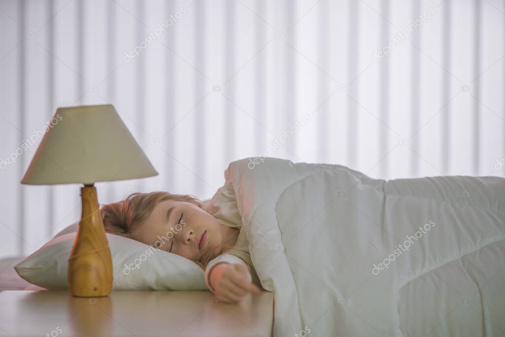 The cute girl sleeping on the bed with white linens