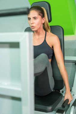 Sporcu kadın spor salonunda bacak egzersizi yapıyor.