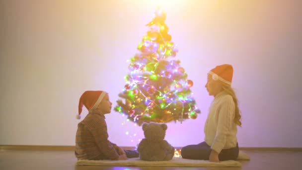 男孩和一个女孩在圣诞树旁的地板上玩耍 — 图库视频影像