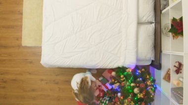 Gülümseyen kız yatağın üzerine uzandı ve Noel ağacının yanında gülümsedi.