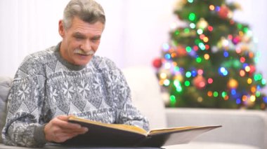 Mutlu emekliler Noel ağacının yanında bir fotoğraf albümü izler.