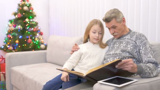 Der Glückliche Großvater Und Ein Mädchen Betrachten Ein Fotoalbum Neben — Stockvideo