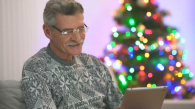 Emekliler Noel ağacının yanında bir tabletle konuşuyor. Akşam vakti.