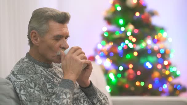 Velho Feliz Senta Com Uma Xícara Chá Perto Árvore Natal — Vídeo de Stock