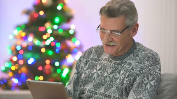 クリスマスツリーの近くのタブレットと幸せな年金受給者の話 — ストック動画