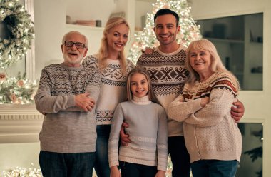 Mutlu aile Noel ağacının arkasında duruyor.