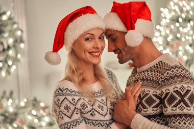 Mutlu adam ve kadın yılbaşı ağacının arka planında duruyorlar.