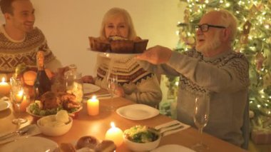 Aile, Noel ağacı arka planında yemek yiyor.