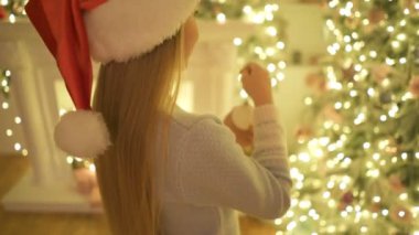 Küçük kız Noel ağacını süslüyor.