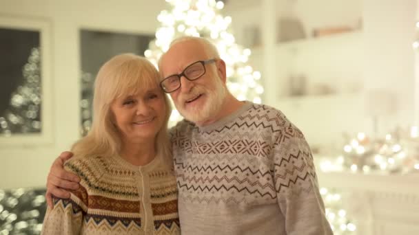 老人和一个女人拥抱在圣诞树的背景上 — 图库视频影像
