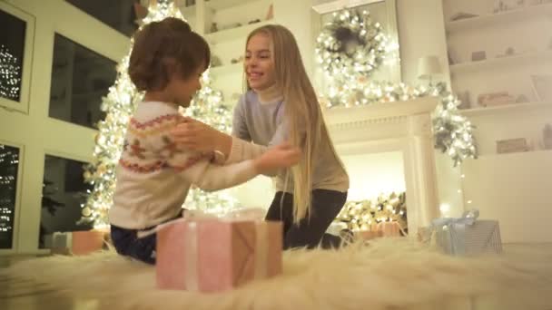 女の子と男の子はクリスマスツリーの背景に床で遊ぶ — ストック動画