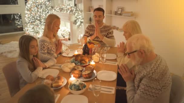Счастливая Семья Молится Столом Фоне Рождественской Елки — стоковое видео