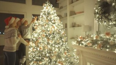 Ailesi olan kız Noel ağacını süslüyor. yavaş çekim