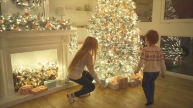 Çocuklar Noel ağacının yanında hediyeler tutuyorlar. yavaş çekim