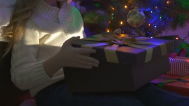 Noel ağacının yanındaki hediye kutusunu açan kız.