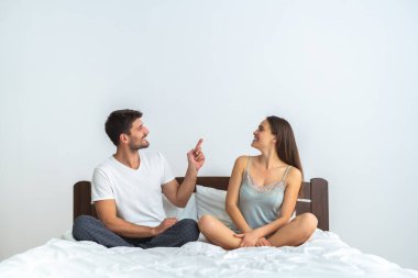 Genç çift yatakta oturuyor ve el kol hareketi yapıyor.