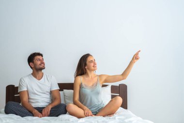 Yatakta oturup el kol hareketi yapan mutlu çift.