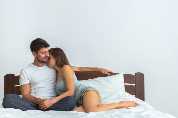 幸せなカップルは 白い背景にベッドの上に抱擁 — ストック写真