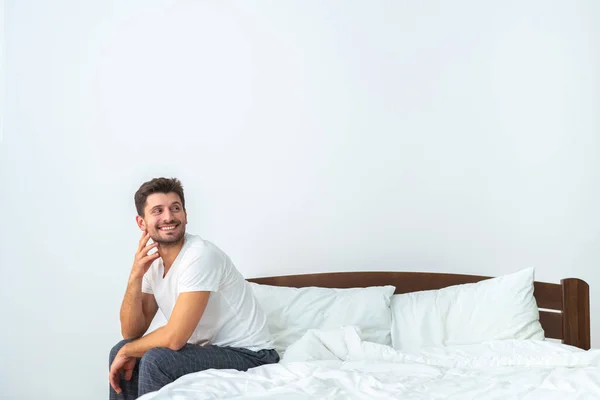 Ευτυχισμένος Άνθρωπος Που Κάθεται Στο Κρεβάτι Στο Λευκό Φόντο — Φωτογραφία Αρχείου