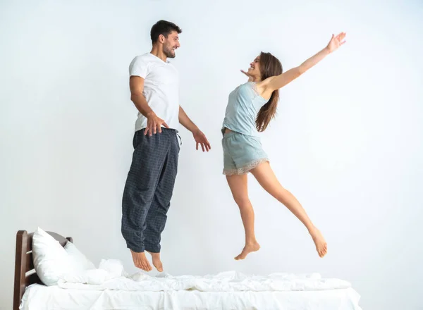Den Lyckliga Mannen Och Kvinna Hoppar Sängen Den Vita Bakgrunden — Stockfoto