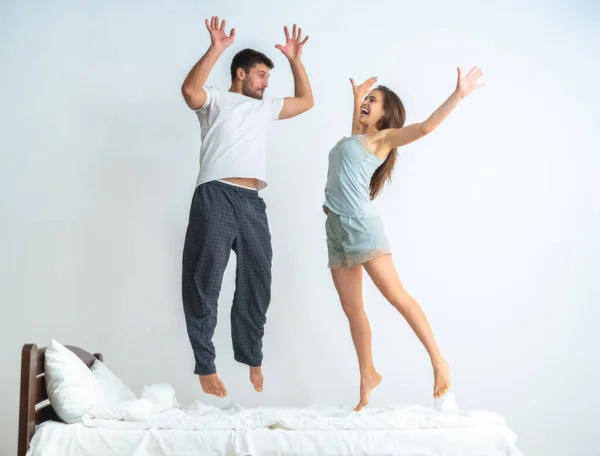 Pareja Saltando Sobre Cama Sobre Fondo Blanco —  Fotos de Stock