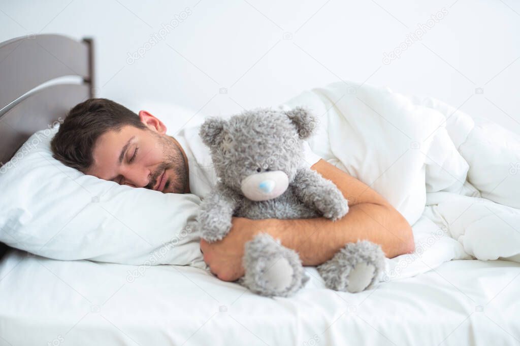 The man sleeping with a soft toy on the white background