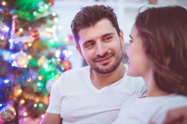 Mutlu çift Noel ağacının yanında oturuyor.