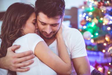 Mutlu çift oturur ve Noel ağacının yanında sarılırlar.