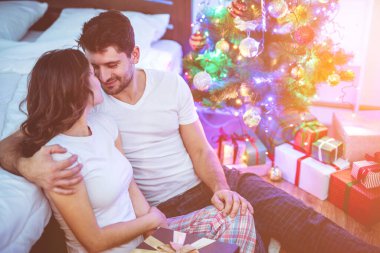 Adam ve kadın Noel ağacının yanında oturuyor.