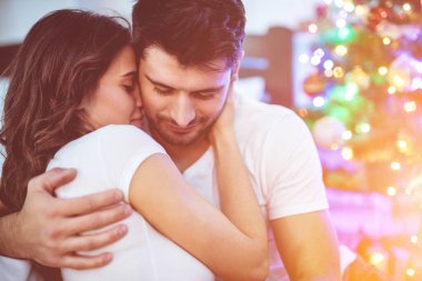 Romantik çift Noel ağacının yanında sarılıyor.