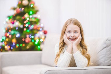 Küçük kız noel ağacının yanındaki kanepede uzandı.