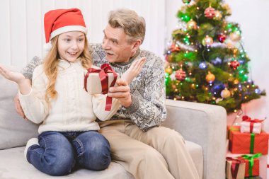 Mutlu büyükbaba küçük bir kıza hediye kutusu veriyor.