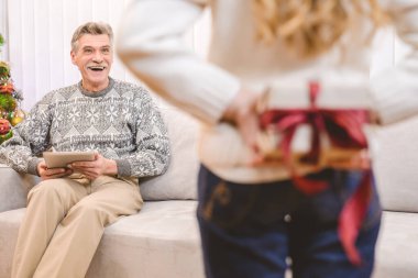 Küçük kız büyükbabası için bir hediye kutusu tutuyor.