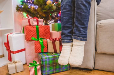 Bir çocuğun bacakları hediye kutularının yanında.