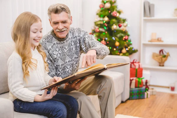 Menina Com Avô Olha Para Álbum Fotos Perto Árvore Natal — Fotografia de Stock