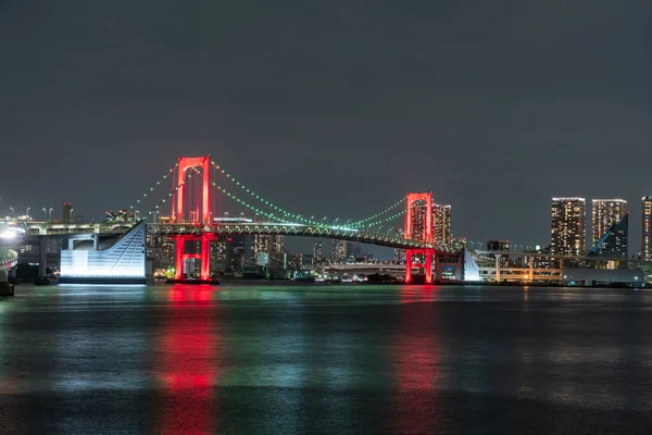 お台場の 東京警報 東京周辺のコロナウイルス警報 の標識として赤くライトアップされたレインボーブリッジの夜景 ロイヤリティフリーのストック画像