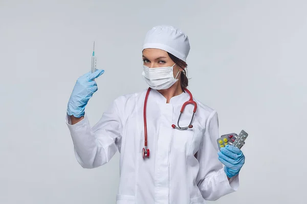 Medical concept of a female doctor in a white coat with a stethoscope, doctor. A female hospital worker looks at the camera and smiles, Studio, White background