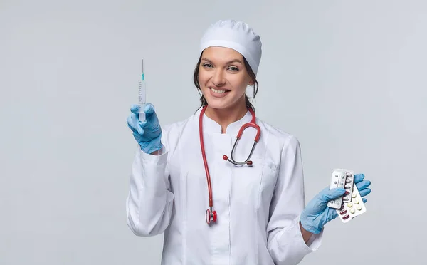 Medical concept of a female doctor in a white coat with a stethoscope, doctor. A female hospital worker looks at the camera and smiles, Studio, White background