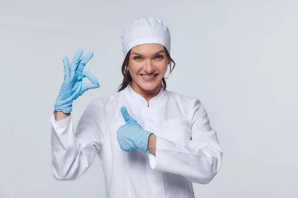 Medical concept of a female doctor in a white coat with a stethoscope, doctor. A female hospital worker looks at the camera and smiles, Studio, White background