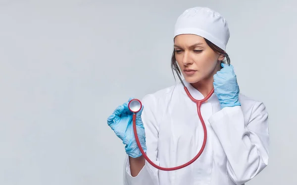 Medical concept of a female doctor in a white coat with a stethoscope, doctor. A female hospital worker looks at the camera and smiles, Studio, White background